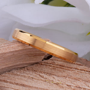 Yellow gold tungsten wedding ring showing brushed finish and beveled edges on a wooden surface.