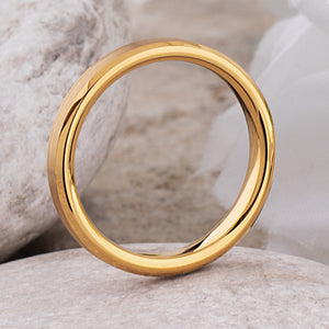yellow gold tungsten wedding ring showcasing a polished finish and beveled edges on a stone background