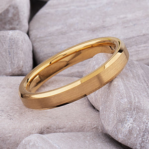 Yellow gold tungsten wedding ring with brushed finish and beveled edges on stone background.