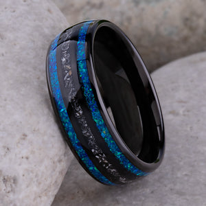 Black domed tungsten wedding ring with genuine meteorite center inlay and shimmering green-blue opal side inlays.